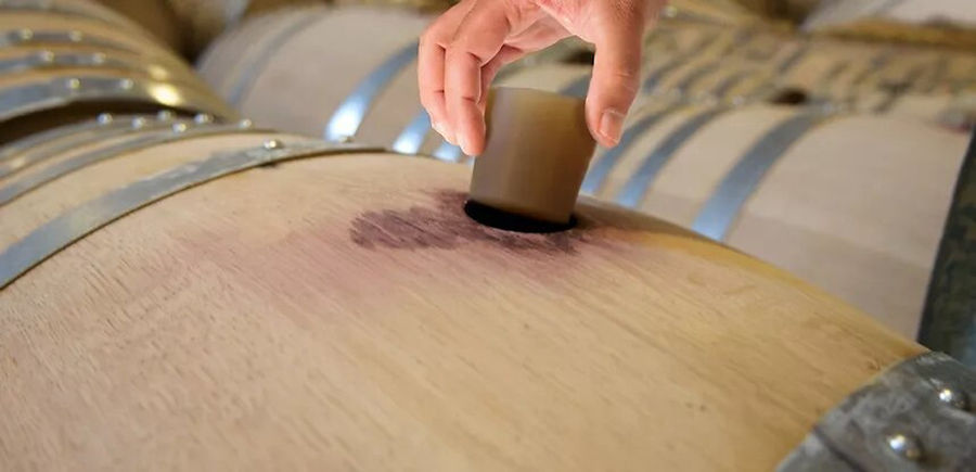man covered a wine barrel with a bung at Ktima Spiropoulos cellar